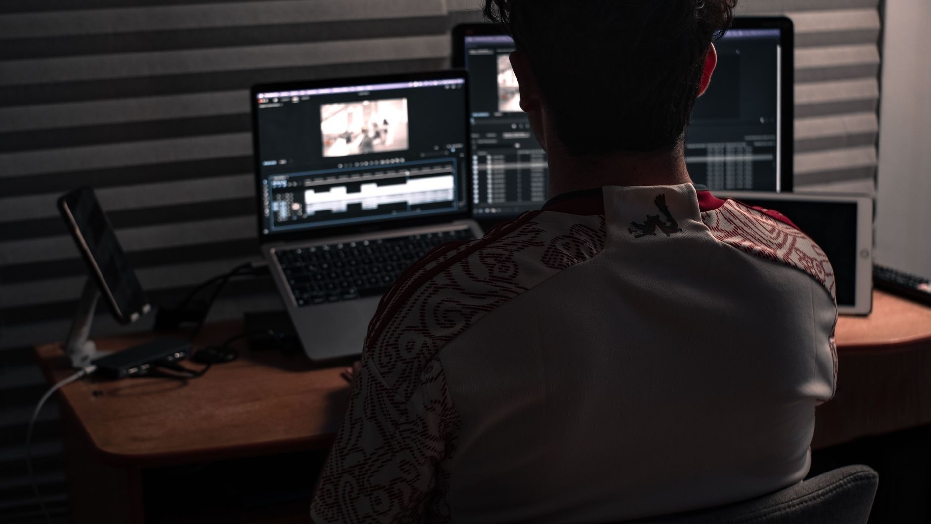 Filmklipper arbeider ved laptop og to skjermer med videoredigering